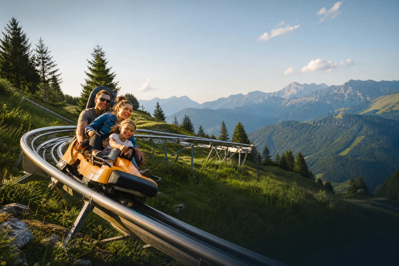 Familie auf einer Sommerrodelbahn in den Bergen